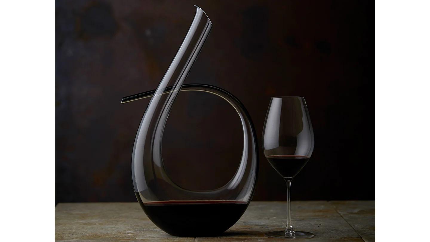 A glass of 17th Anniversary release Grenache/Shiraz 2022 sitting next to it's decanter